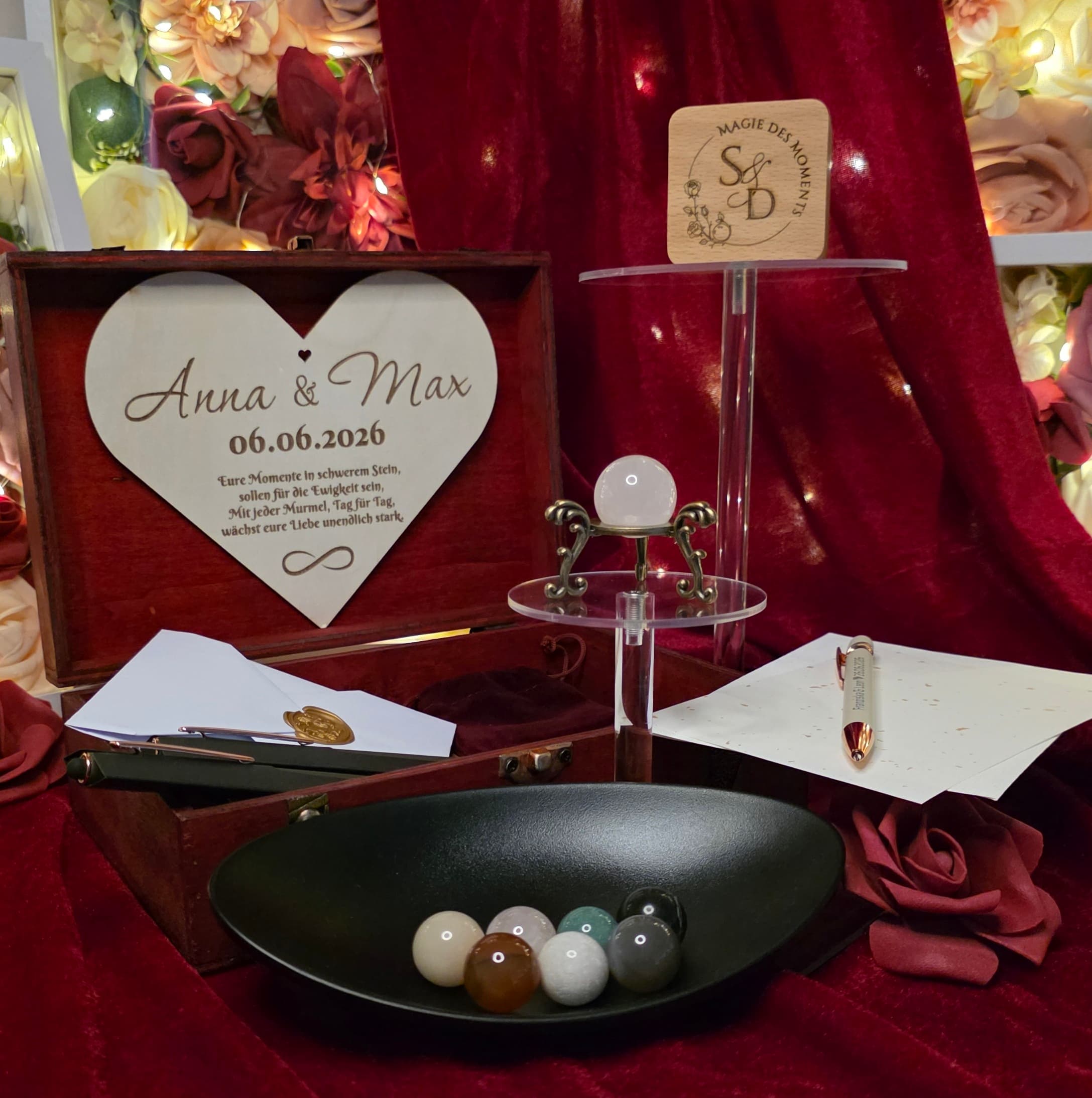 Gravierte Momentemurmel-Box mit leuchtender Murmel auf goldenem Ständer, Kerze und Rosen